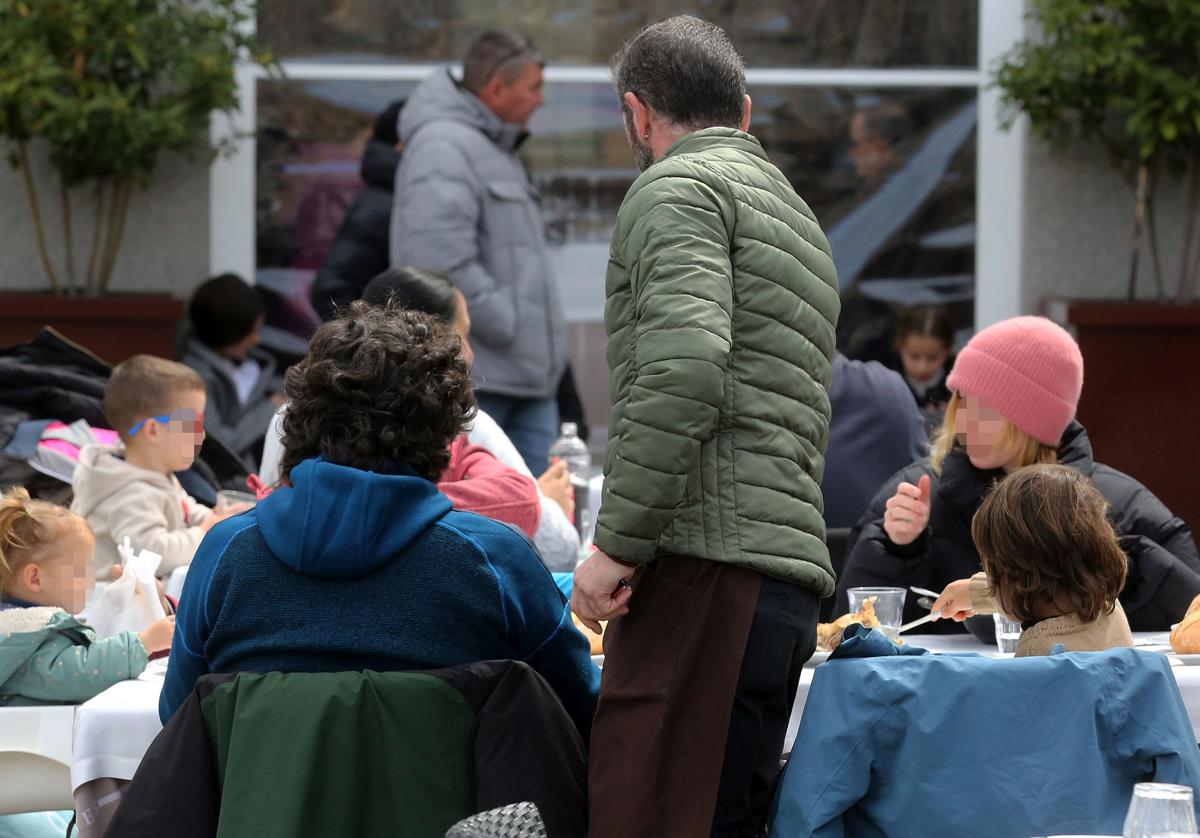 Un camarero de un restaurante de Segovia atiende una mesa de la terraza del establecimiento.