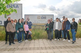 Los afectados posan junto a un cartel de la promoción situado en el solar donde estaba previsto levantar el bloque de viviendas.