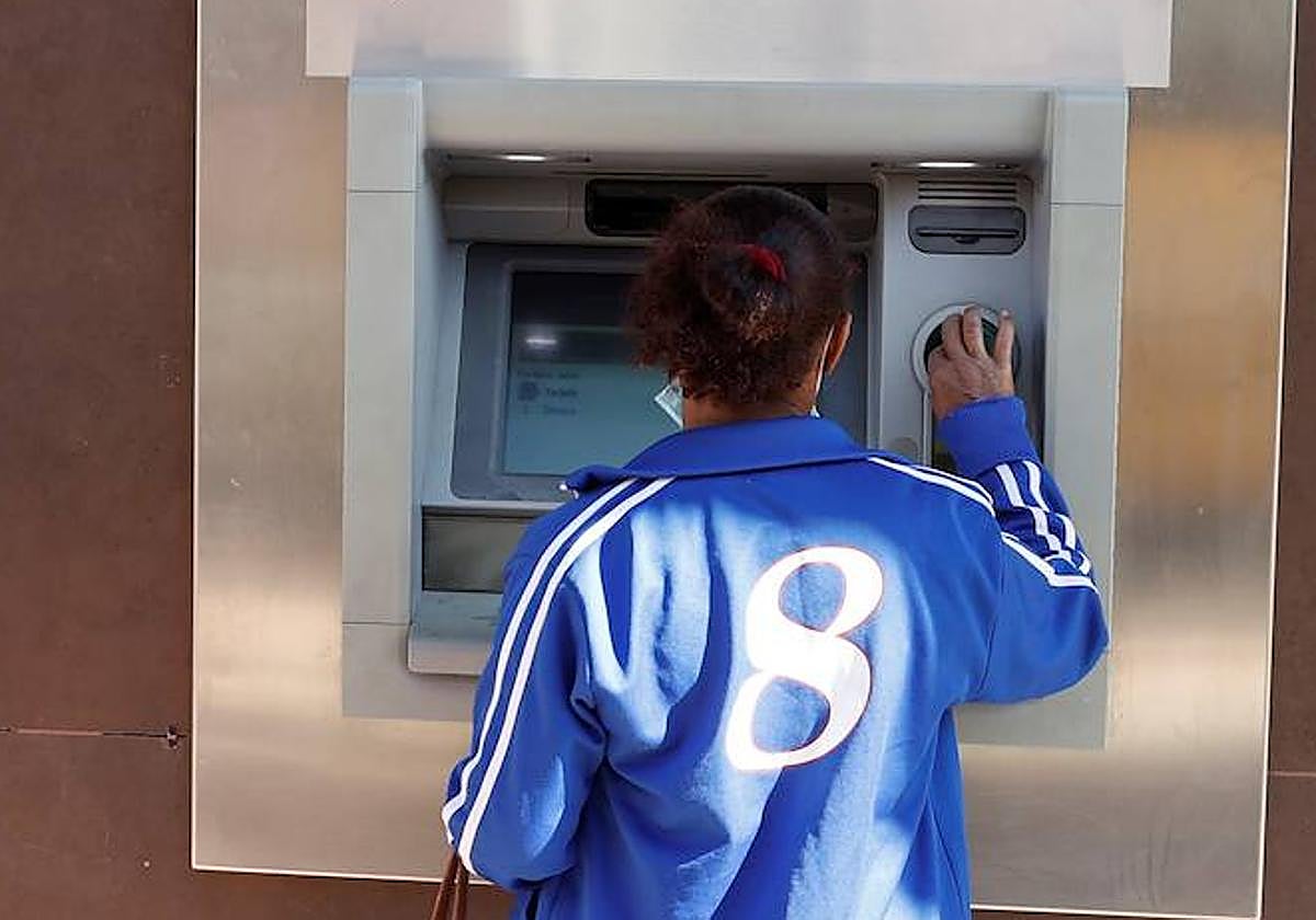 Una mujer saca dinero en un cajero automático.
