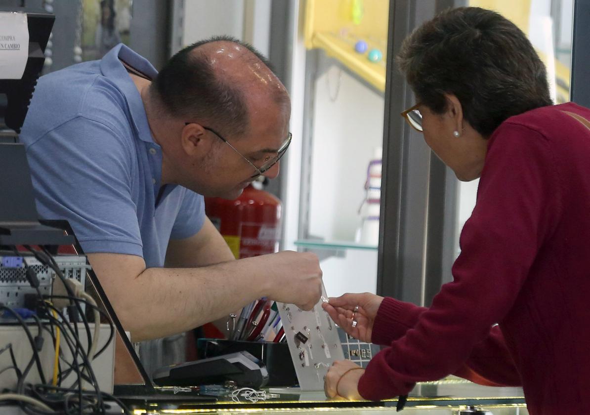 Un comerciante de la ciudad de Segovia enseña un producto a una clienta.