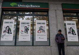 Un hombre ante una sucursal de Unicaja Banco.