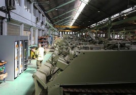 Dos trabajadores de la Base Mixta, junto a decenas de tanques reconstruidos.