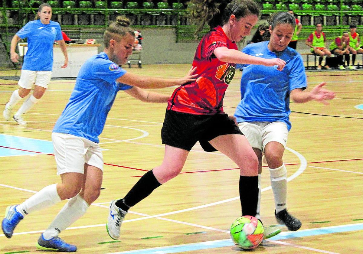 Una jugadora del Segosala trata de llevarse la pelota ante dos rivales en un encuentro anterior.