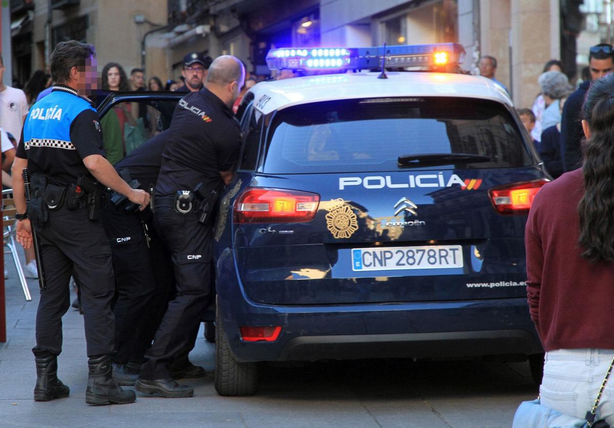 La Policía Nacional, con la colaboración de agentes locales, introducen a un detenido en la Calle Real de Segovia.