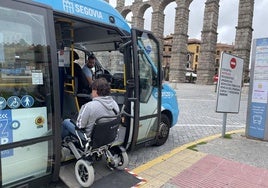 Un hombre en silla de ruedas sube a un autobús en una parada junto al Acueducto.