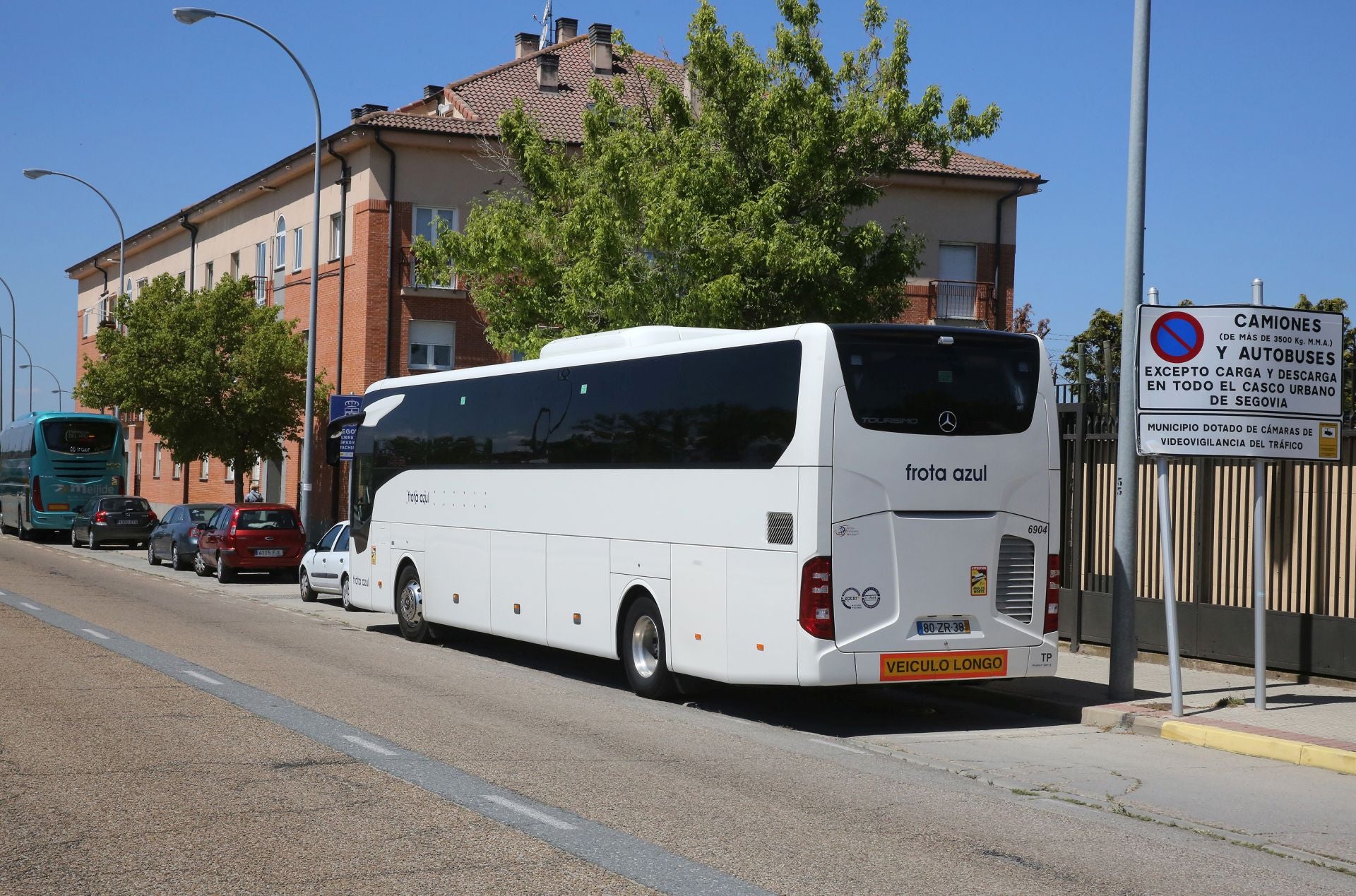 Autobús aparcado en la carretera de Riaza junto a una señal que informa de la prohibición de aparcar a camiones y autobuses.