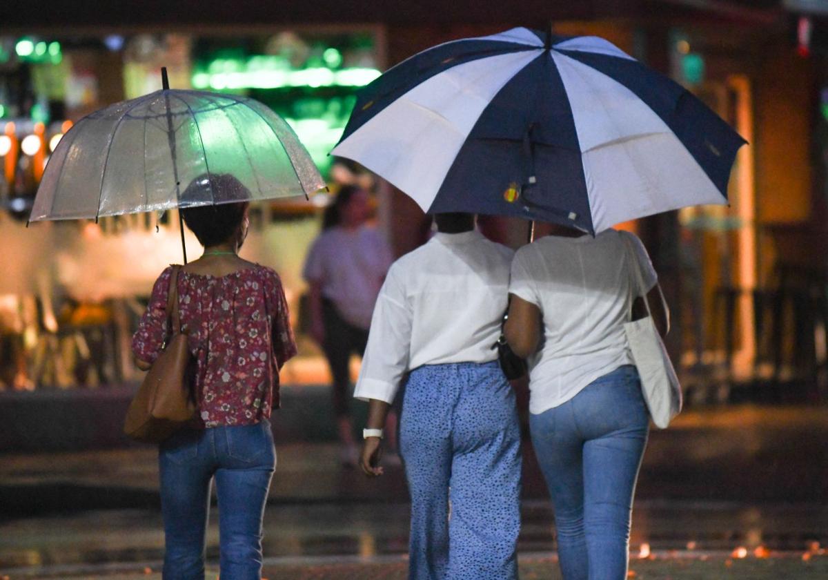 Tres mujeres se protegen de la lluvia el pasado verano en Valladolid.