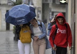 Algunos peatones se protegen de la lluvia.