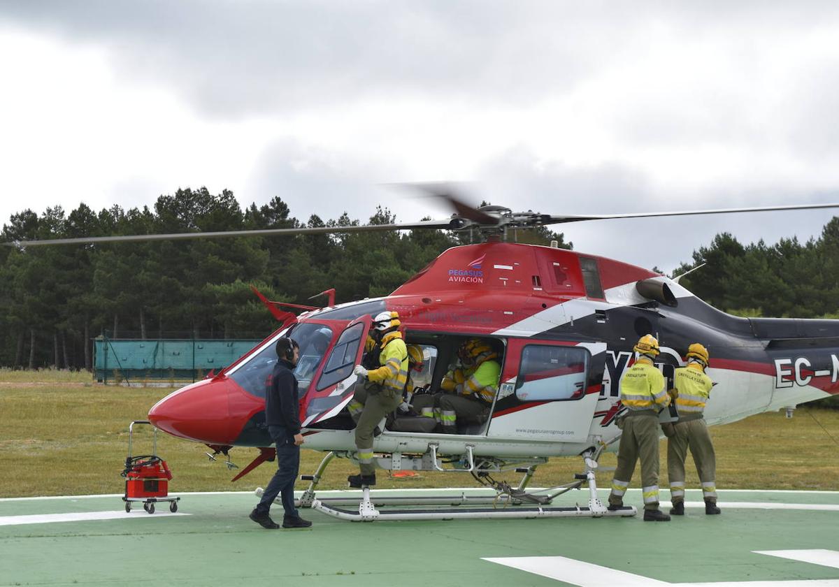 Personal de los equipos contra incendios suben al helicóptero, este viernes en la base de Villaeles.