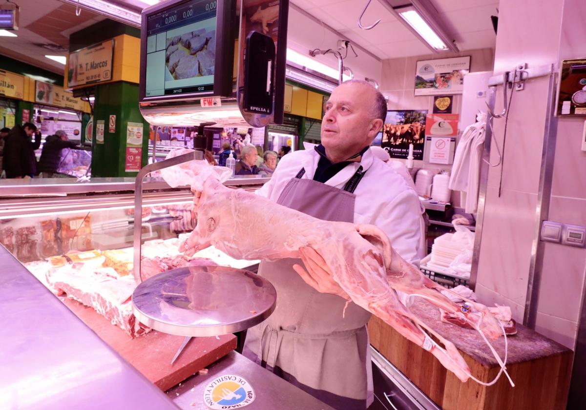 Un carnicero con un lechazo en su puesto del Mercado del Campillo de Valladolid.