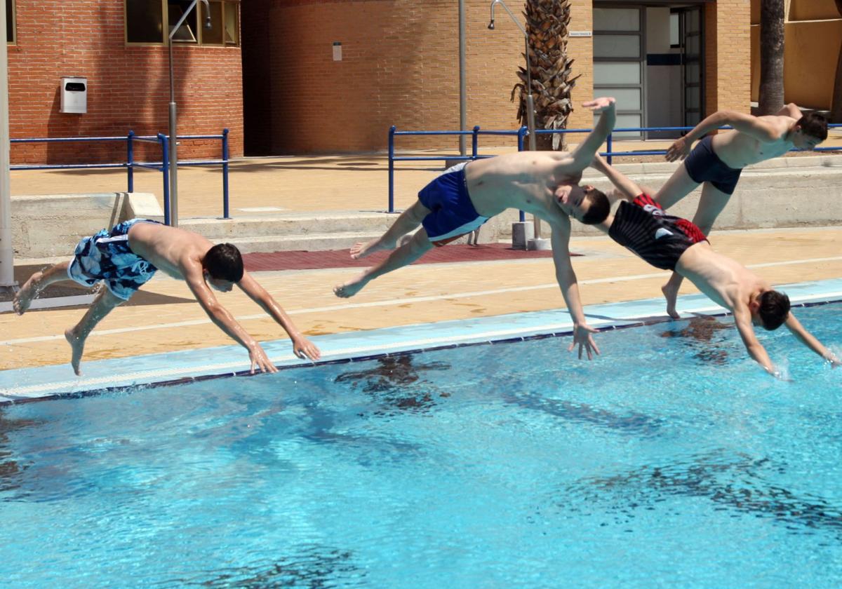 Varios adolescentes se lanzan de cabeza a la piscina.