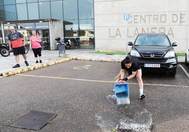 Una empleada de La Lanera vacía un cubo en una alcantarilla.