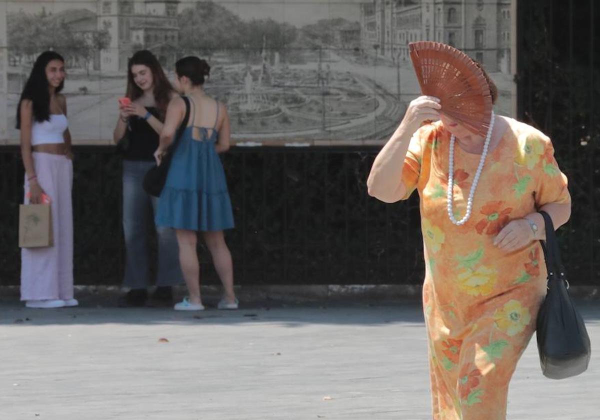 Una mujer se protege del calor con un abanico mientras camina por la plaza de Zorrilla.