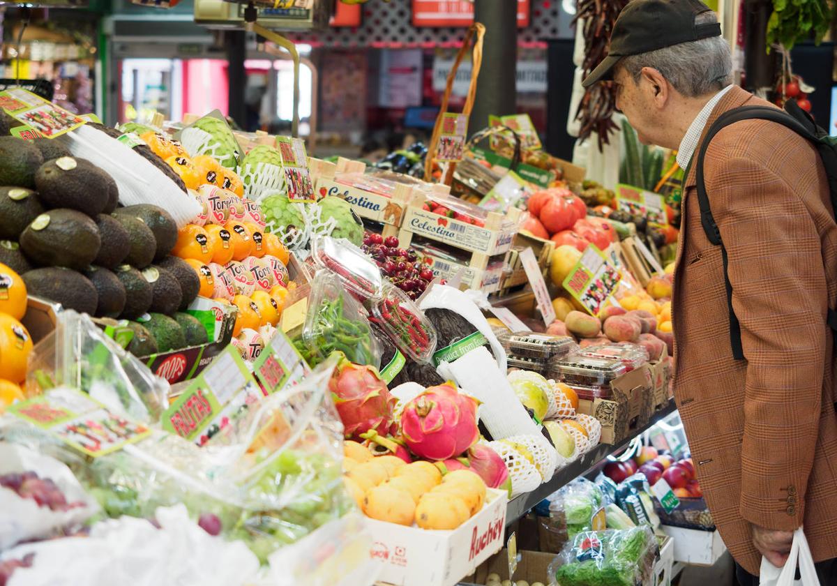 Una persona observa un puesto de frutas y verduras.