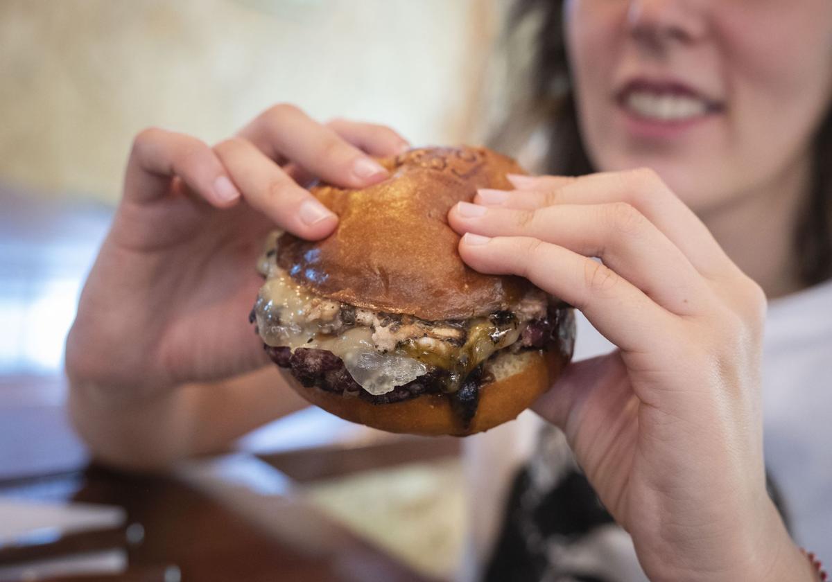 Una joven va a consumir una hamburguesa.