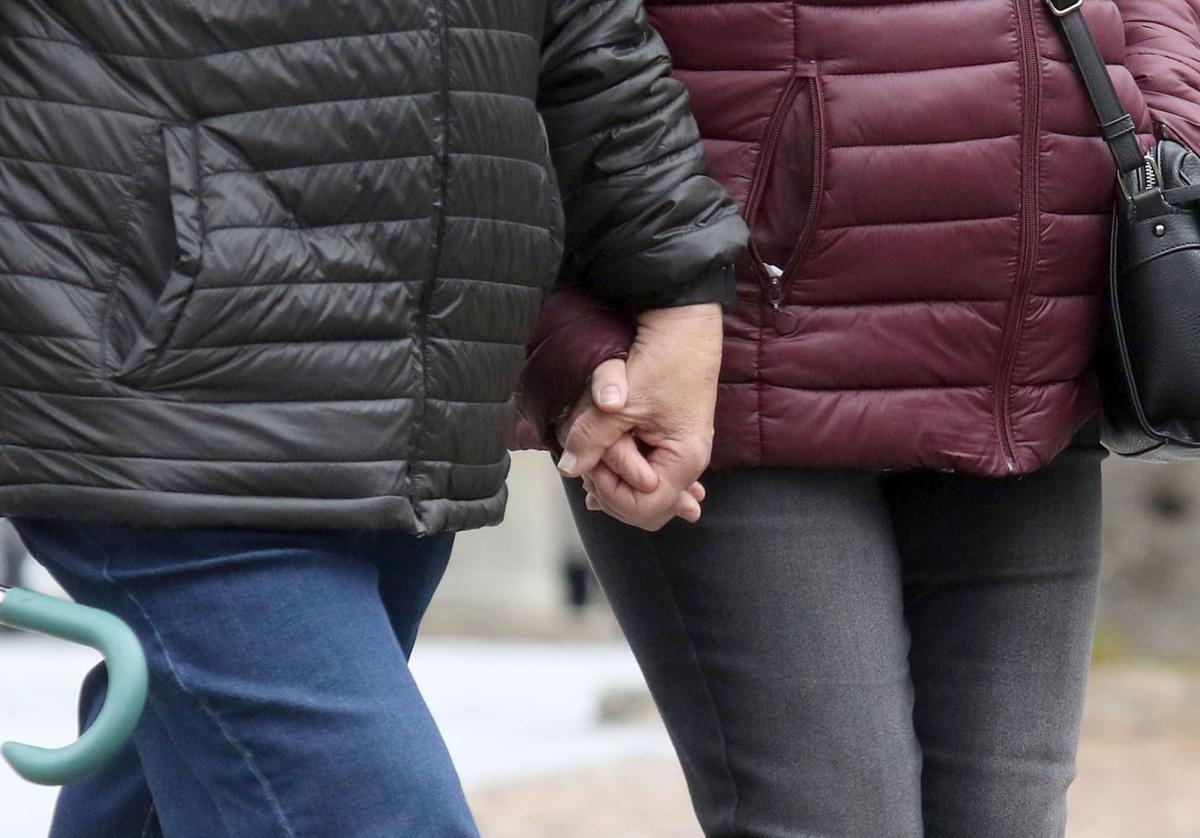 Una pareja caminando por la calle de la mano.