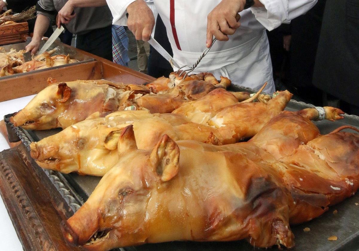 Un cocinero se dispone a trinchar unos cochinillos.