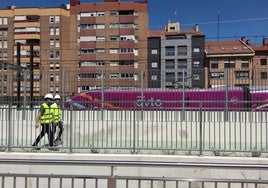 El concejal y uno de los técnicos de las obras recorren el carril bici pegado a la valla, en la calle Guipuzcoa, mientras pasa un Avlo.