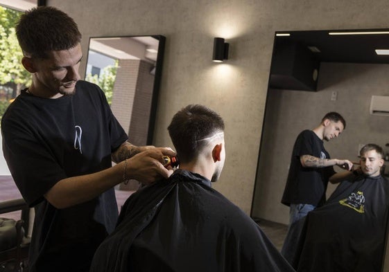 El barbero Carlos Yllera corta el pelo a un cliente.