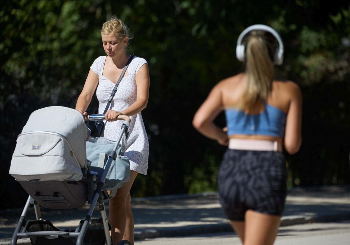 Una mujer empuja un carrito de bebé.