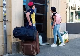 Estudiantes con los equipajes se disponen a entrar en el portal de su vivienda en Segovia.