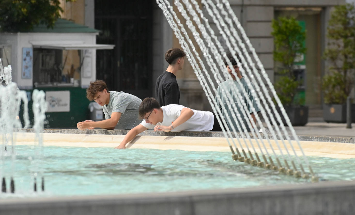 Un grupo de jóvenes se refresca en la fuente de Zorrilla este martes por la tarde.