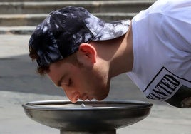 Un joven bebe agua para hidratarse en una fuente durante estos días de calor en Segovia.