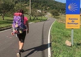 Una peregrina avanza por una carretera del Camino de Santiago.