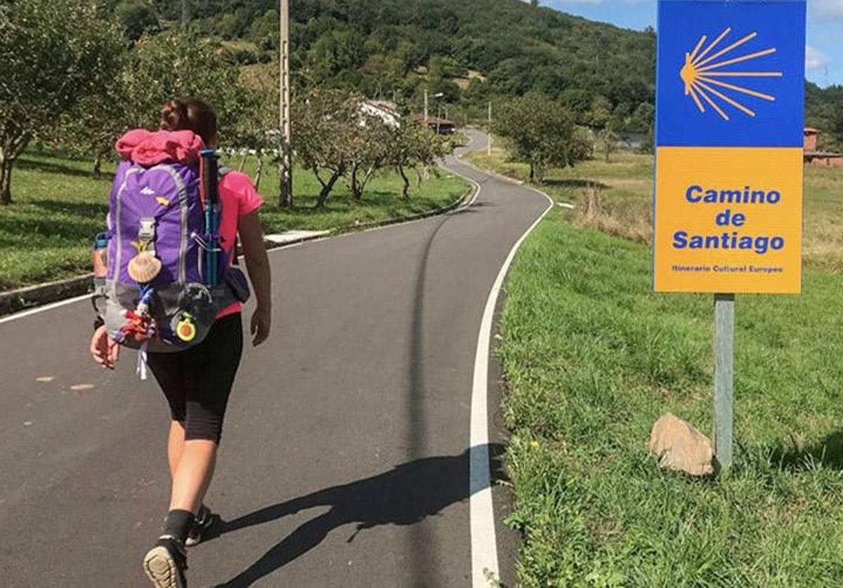 Una peregrina avanza por una carretera del Camino de Santiago.