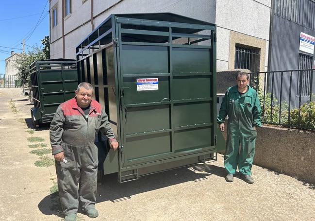 Los dos herreros junto a uno de los remolques fabricados en su taller.