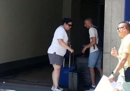 Turistas con maletas esperan a la puerta de un alojamiento en la ciudad de Segovia.