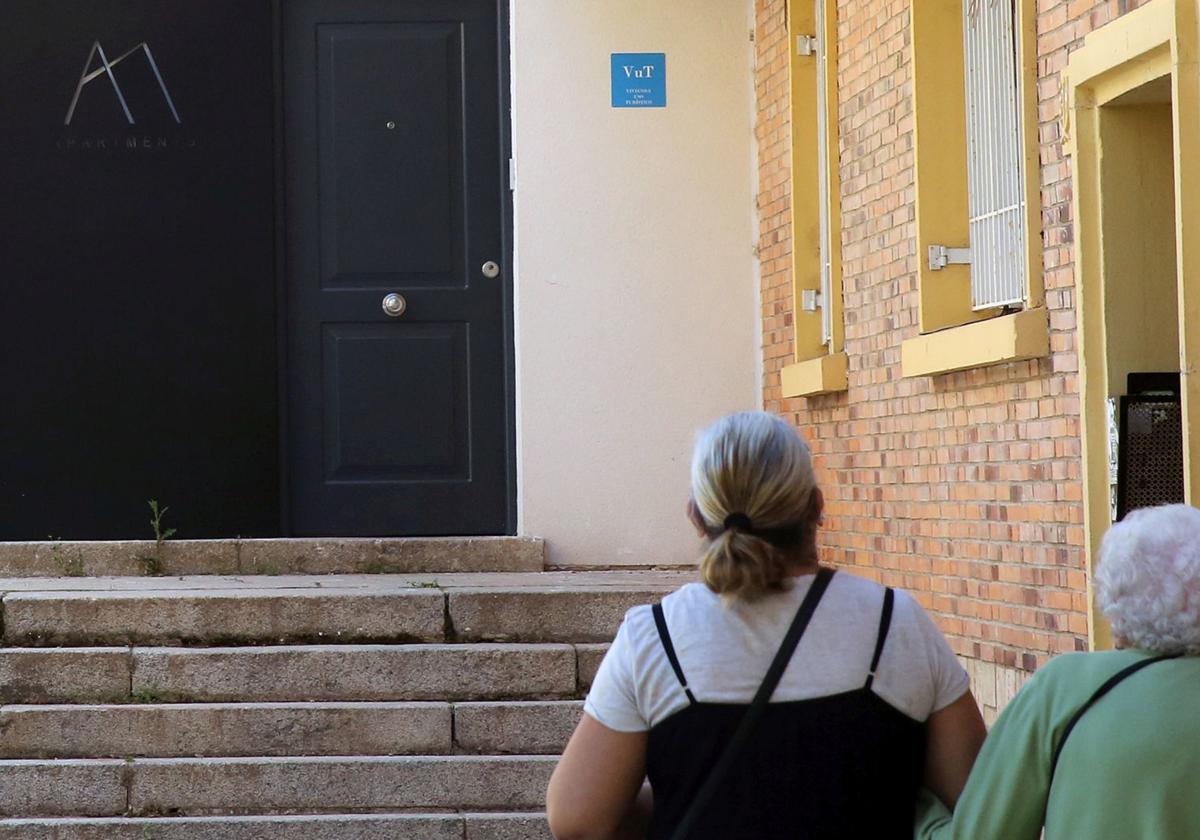 Dos personas observan el cartel de una vivienda de uso turístico en Segovia.