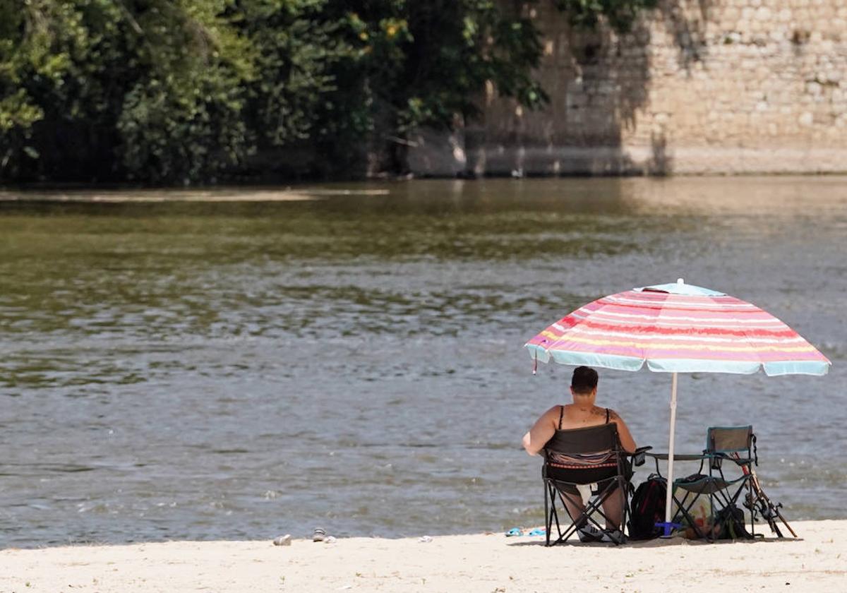 Una mujer se refresca junto al Pisuerga en la playa de Moreras.