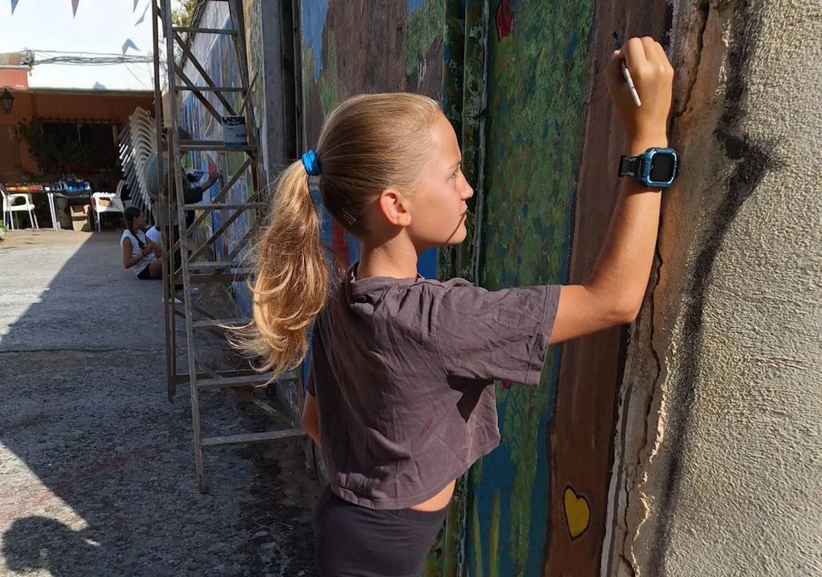 Una niña pinta en el mural.