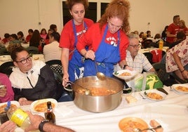 Peñistas sirven el guiso de patatas con carne a los comensales.