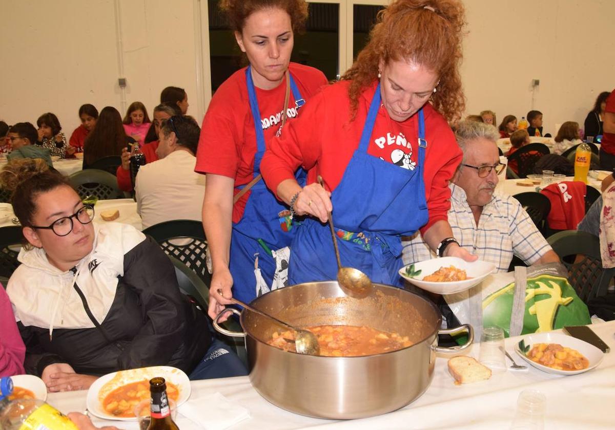 Peñistas sirven el guiso de patatas con carne a los comensales.