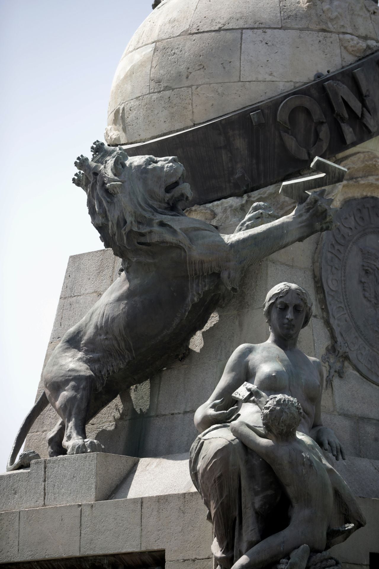 León que sube por la estatua de Colón.