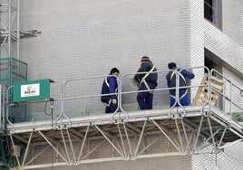 Obreros en un andamio trabajando en el exterior de un edificio en construcción.