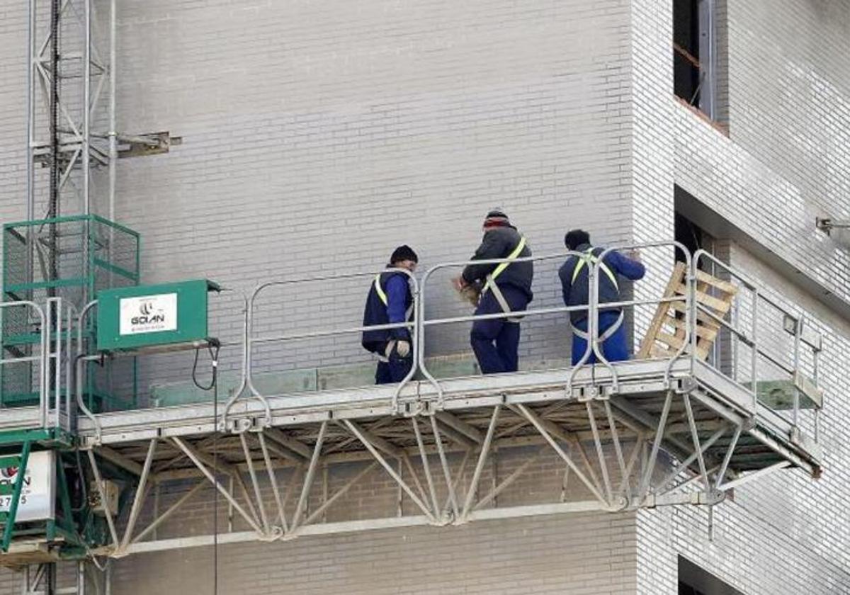 Obreros en un andamio trabajando en el exterior de un edificio en construcción.