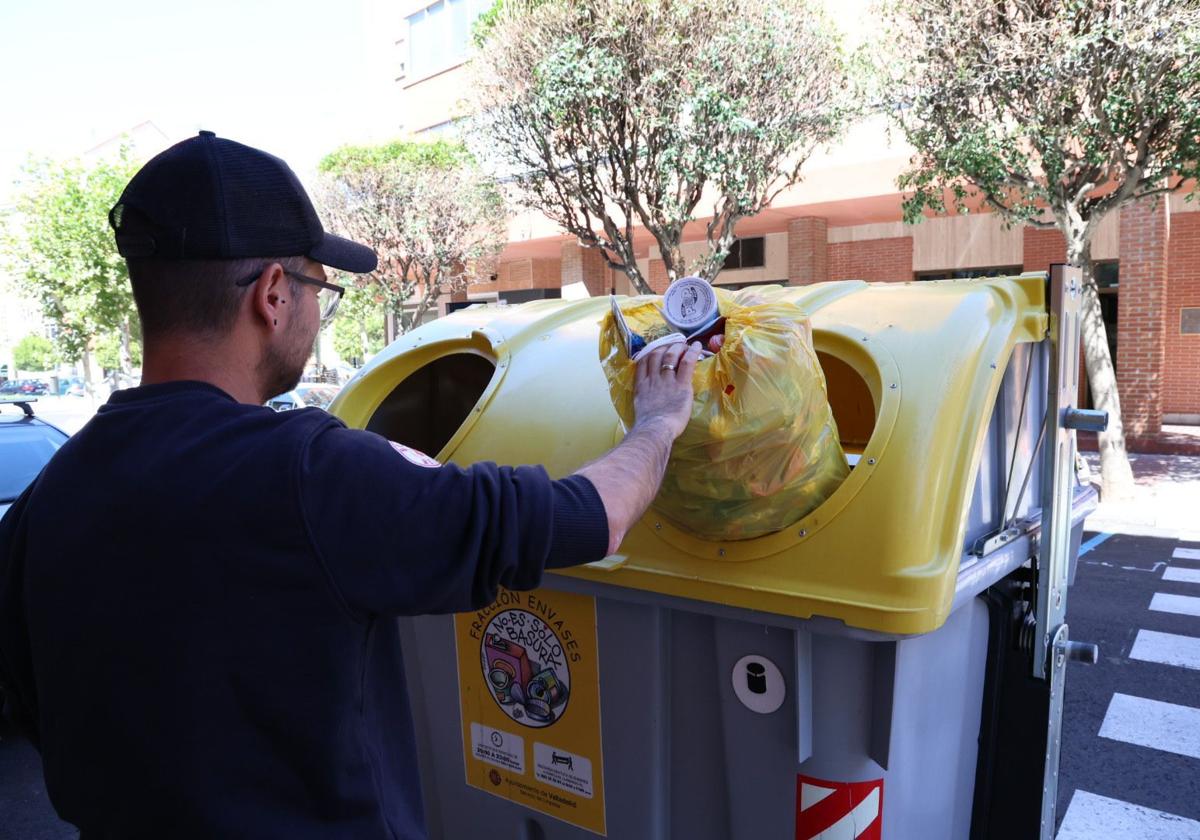 Un joven deposita la envases en un contenedor.