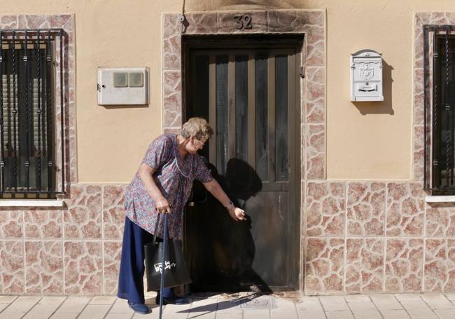 La madre de Beatriz y Azucena enseña los desperfectos en su puerta tras el incendio.