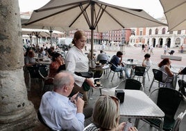 Un camarera atiende a unos clientes en una terraza.