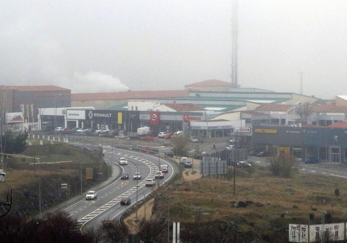 Multitud de coches circulan por un vial junto a un área industrial de la ciudad de Segovia.