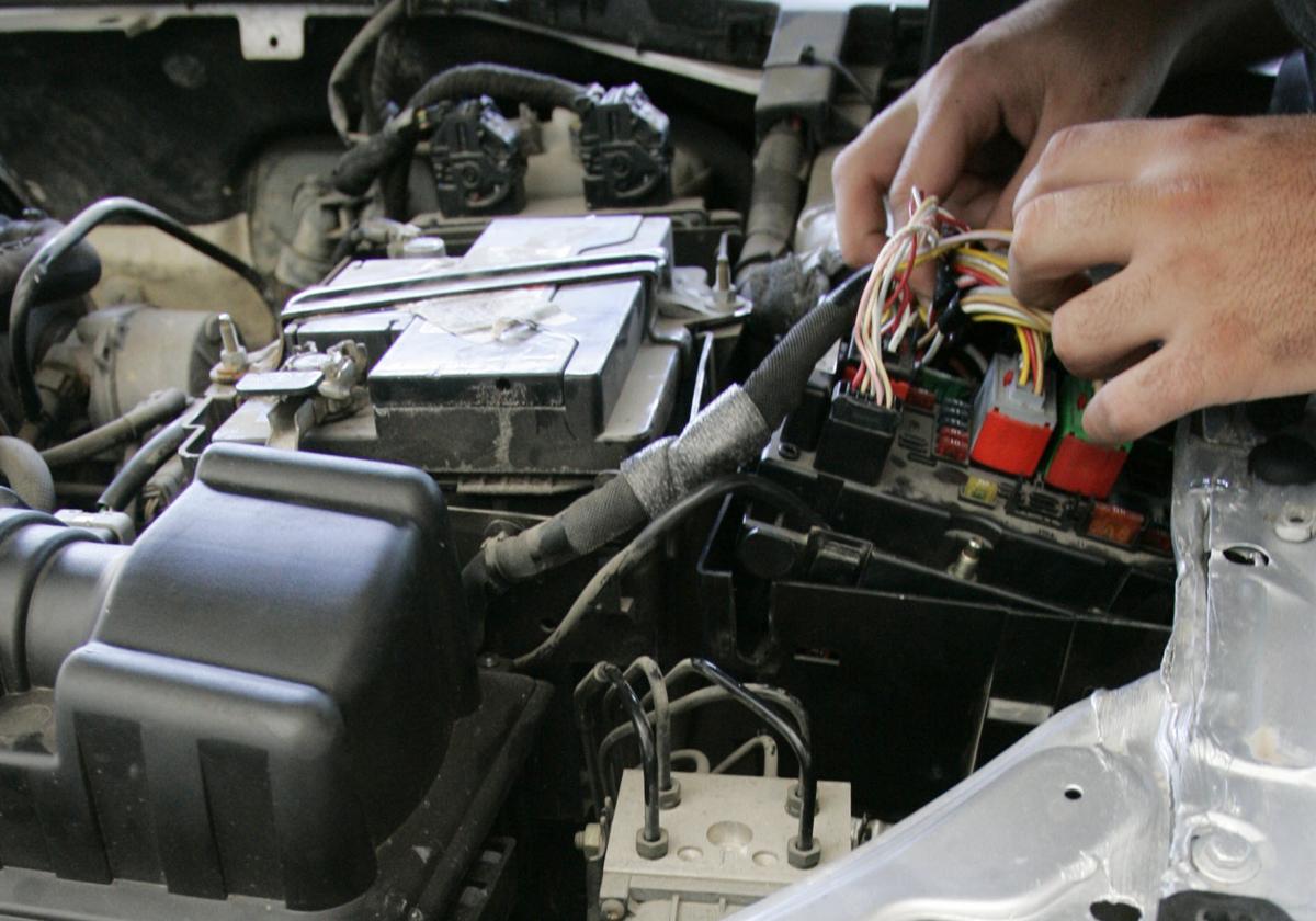 Mecánico manipula el cableado del interior de un vehículo, en imagen de archivo.