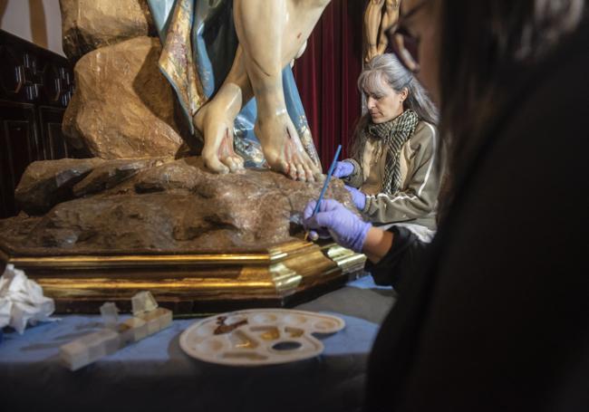 Las especialistas actúan en los craquelados de la policromía para restaurar la pintura.