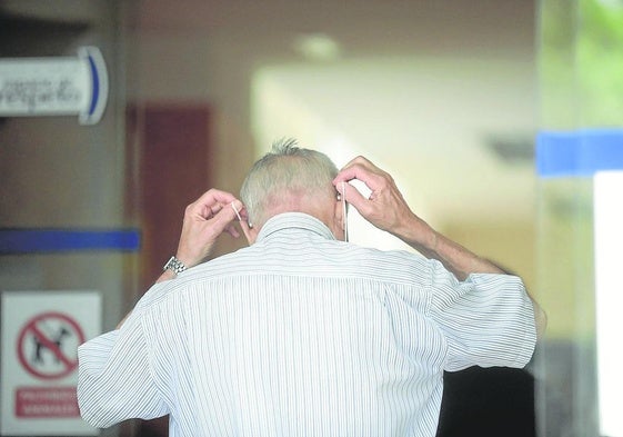 Un hombre mayor se coloca una mascarilla para entrar en un centro de salud.