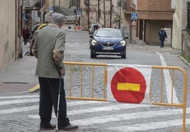 Un hombre pasea junto a una valla por la realización de obras en Segovia capital.