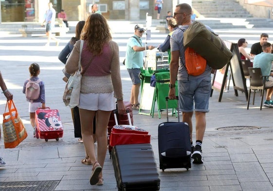 Turistas se dirigen a su establecimiento hotelero en la ciudad con sus maletas.