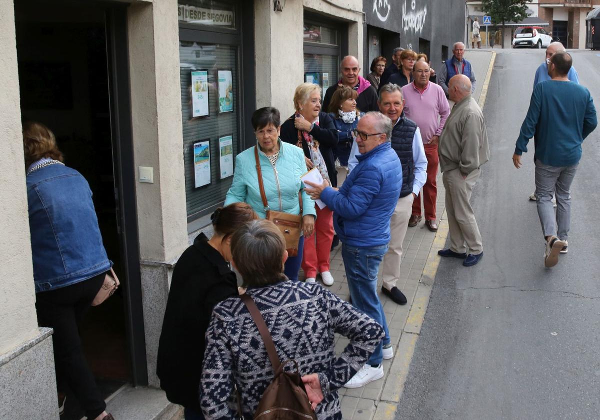 Varias personas esperan en una cola a las puertas de una agencia de viajes.