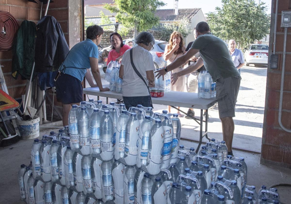 Varias personas participan en el reparto de agua en un pueblo segoviano en verano de 2023.